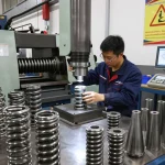 Tehnician inspectând arcuri oțel într-un atelier de fabricație a arcurilor metalice, cu diverse arcuri și unelte.